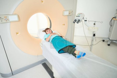 Téléchargez les photos : Enfant couché sur la surface mobile de la machine CT dans un centre médical - en image libre de droit