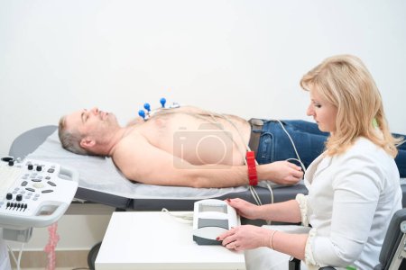 Photo for Male patient getting heart rate monitored with electrocardiogram equipment. Cardiogram test - Royalty Free Image