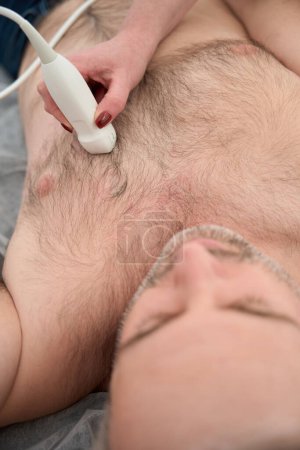 Photo for Close up of heart ultrasound examination performed by female doctor with adult male patient - Royalty Free Image