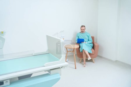 Photo for Adult man patient completing the questionnaire in a doctor office before medical examination - Royalty Free Image