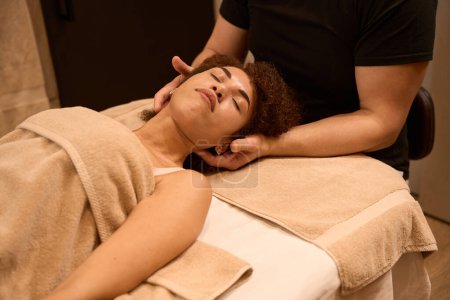 Foto de Masaje Masculino terapeuta haciendo su trabajo a cliente femenino con los ojos cerrados en la sala de masajes - Imagen libre de derechos
