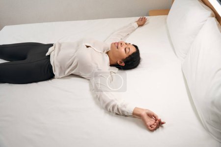 Foto de Sonriente mujer feliz turista acostada en la cama cómoda en su suite de lujo - Imagen libre de derechos