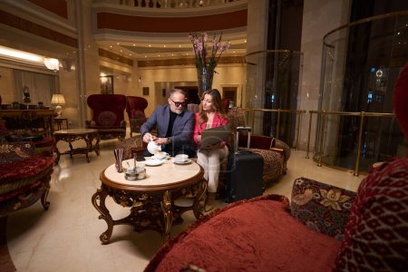 Photo for Man and a woman with a laptop communicate in a cozy relaxation area, tea is served for two - Royalty Free Image