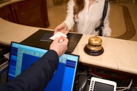 Photo for Lady in travel clothes is checking in at the reception desk, the porter at her workplace at the counter - Royalty Free Image