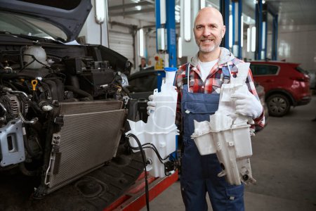 Téléchargez les photos : Travailleur remplace un réservoir dans une voiture, les réparations sont effectuées dans un atelier de réparation automobile - en image libre de droit