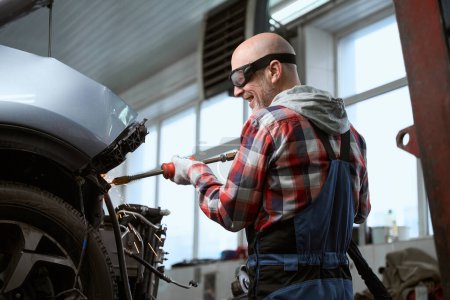 Foto de Reparador de automóviles en gafas de reparación de un coche después de un accidente, un hombre utiliza un observador - Imagen libre de derechos
