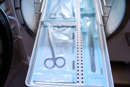 Medical instruments is lying on a special grid and it is inserting into the autoclave for sterilization