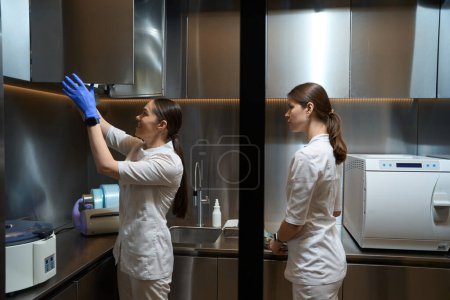 Foto de Las asistentes médicas están de pie y trabajando en una sala de laboratorio con equipo - Imagen libre de derechos