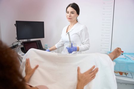 Téléchargez les photos : Médecin gynécologue femelle est assis et faire une échographie transvaginale d'un patient dans le bureau des cliniques - en image libre de droit