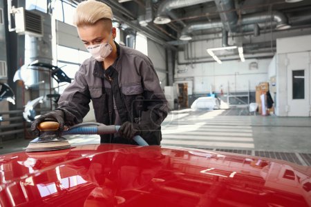 Photo for Caucasian woman service worker in protective mask and work uniform buffing car at auto service - Royalty Free Image