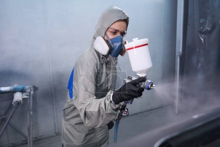 Photo for Professional female employee lost in thought while dyeing in service garage - Royalty Free Image
