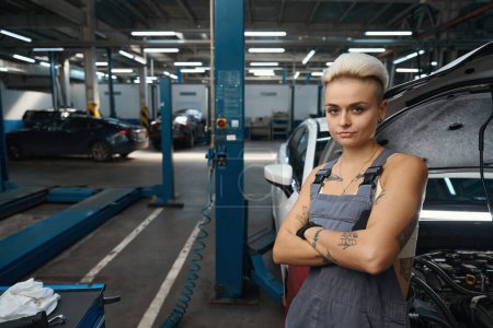 Foto de Mujer reparador de automóviles se encuentra en el lugar de trabajo en la caja de trabajo, equipo moderno en el taller - Imagen libre de derechos