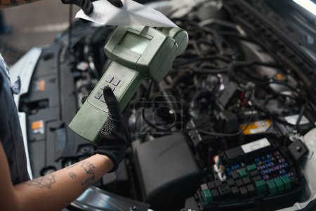 Téléchargez les photos : Auto réparateur tient un scanner spécial dans ses mains, femme en salopette de travail - en image libre de droit