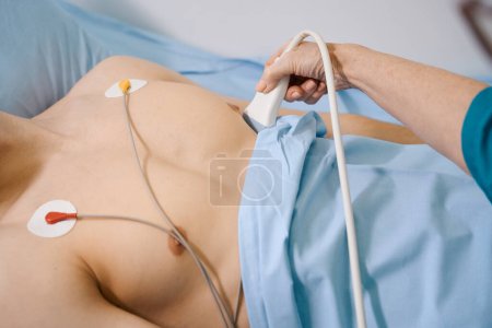 Foto de Hombre con un torso desnudo en un examen médico, el médico comprueba su corazón - Imagen libre de derechos