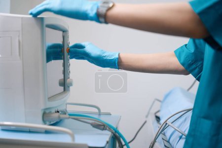 Photo for Medical worker works with a stationary cardiograph in a diagnostic center, a man in protective gloves - Royalty Free Image
