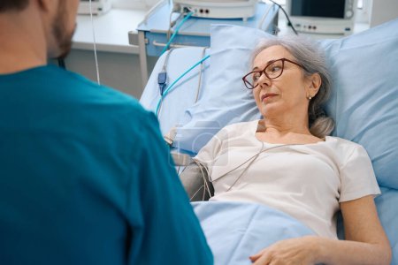 Photo for Elderly patient undergoes examination and treatment in the cardiology department, she is consulted by a young doctor - Royalty Free Image