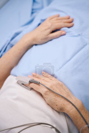 Foto de Mujer mayor se encuentra en una cama de hospital en el departamento de cardiología, ella está conectada a equipos modernos - Imagen libre de derechos