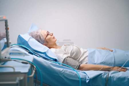 Photo for Patient lies on a hospital bed in the cardiology department, she is connected to modern equipment - Royalty Free Image