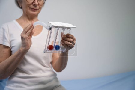 Téléchargez les photos : Récupération femme tient un simulateur de poumon postopératoire dans ses mains, à l'intérieur du simulateur il ya des boules multicolores - en image libre de droit