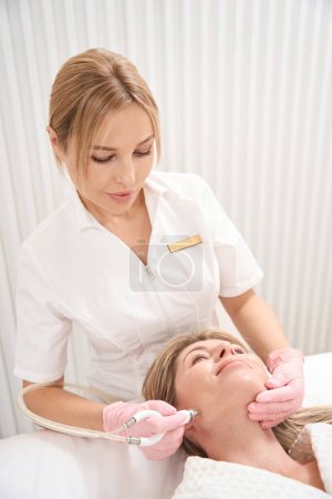 Photo for Woman cosmetologist works with the skin of the patients face, a specialist uses a CO2 laser - Royalty Free Image