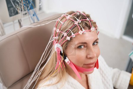Foto de Hermosa mujer en una gorra con electrodos en el procedimiento de electroencefalograma, la paciente en un ambiente cómodo - Imagen libre de derechos