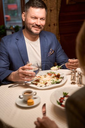 Téléchargez les photos : Heureux mari amoureux proclamant toast en l'honneur de sa belle femme pendant le dîner au restaurant de luxe, célébration - en image libre de droit