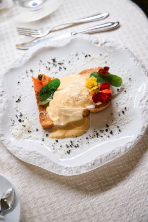 Foto de Estilista aperitivo decorado con tostadas y huevos escalfados se encuentra en un hermoso plato blanco, presentación de la comida en el restaurante - Imagen libre de derechos