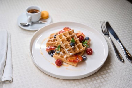 Foto de Delicioso desayuno de café recién hecho y gofres belgas que sirven en la mesa de café - Imagen libre de derechos