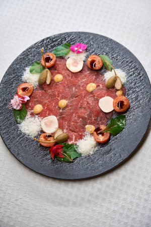 Foto de Restaurante vista superior que sirve de delicioso carpaccio de ternera en elegante plato negro, plato de la semana - Imagen libre de derechos