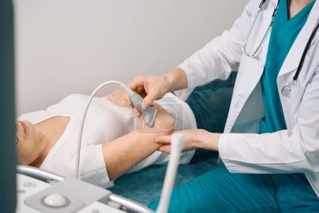 Téléchargez les photos : Femme âgée examine une articulation sur une machine à ultrasons, le médecin utilise un équipement moderne - en image libre de droit