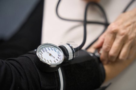 Foto de La persona se mide la presión arterial con un aparato especial, el médico utiliza un tonómetro y un estetoscopio - Imagen libre de derechos