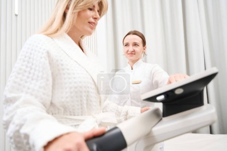 Téléchargez les photos : Femme dans un centre médical subit une procédure de diagnostic bioimpedancemetry, un médecin utilise un équipement moderne - en image libre de droit