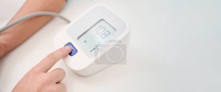 Photo for Measuring blood pressure with a tonometer in a medical facility, the doctor presses the start button - Royalty Free Image