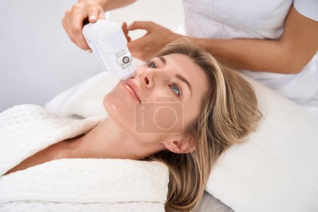 Foto de La mujer cuida su piel facial en una clínica de medicina estética, se somete a un procedimiento de levantamiento de smas - Imagen libre de derechos