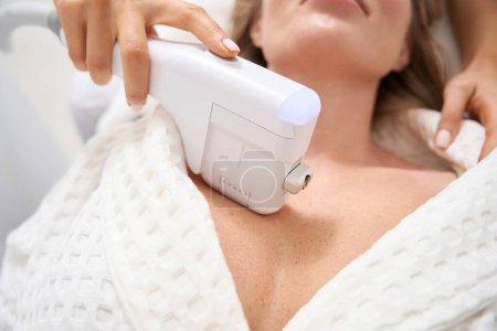 Foto de Mujer en el procedimiento de apriete de la piel no quirúrgica en el área del decolete, el cosmetólogo utiliza un aparato moderno - Imagen libre de derechos