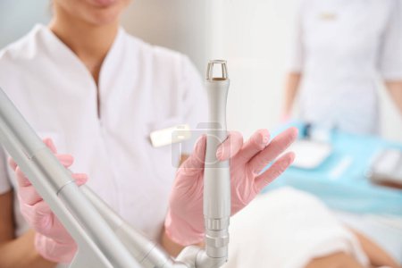 Photo for Employee of the aesthetic medicine clinic holds a laser peeling tool in her hand, the staff uses modern equipment - Royalty Free Image