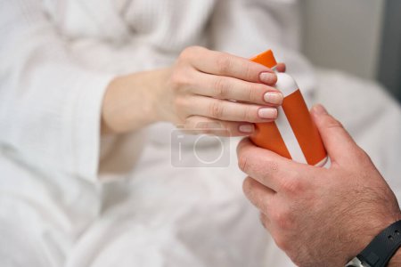 Téléchargez les photos : Cropped view on hand of male doctor passing pill box to female client - en image libre de droit