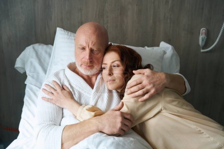 Photo for Loving couple lying on comfortable bed and showing affection to each other in room - Royalty Free Image