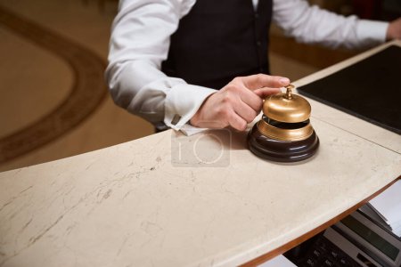 Téléchargez les photos : Gros plan de la cloche de service tactile masculine pour appeler le personnel à la réception dans le hall de l'hôtel - en image libre de droit