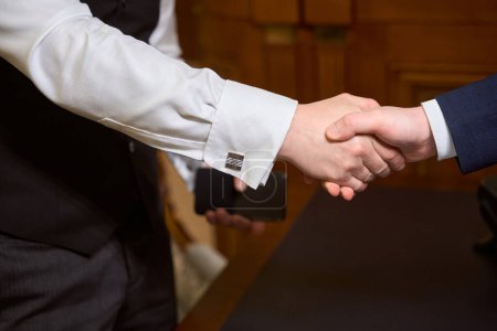 Téléchargez les photos : Gros plan sur les partenaires commerciaux serrant la main après une réunion au bureau - en image libre de droit