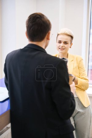 Photo for Back-view man and woman sharing ideas during coffee break in office, resting in lounge zone - Royalty Free Image