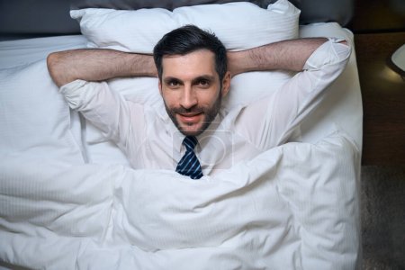 Foto de Hombre, sin desnudarse, descansando en ropa de oficina, en una cama cómoda, se acuesta sobre una almohada suave - Imagen libre de derechos