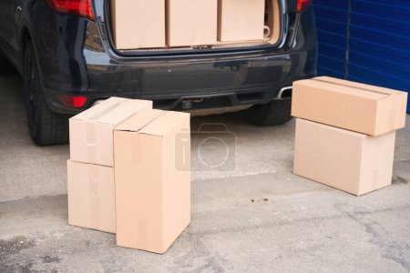 Foto de Hatchback es con cajas de cartón están en el maletero abierto y al lado del coche - Imagen libre de derechos