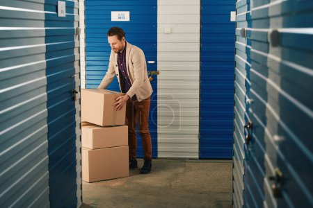 Photo for Young man is stacking big cardboard boxes in storage warehouse - Royalty Free Image