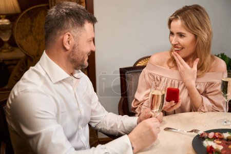 Foto de Elagante caja de espera hombre con anillo para hacer proponer a su mujer sorprendida en la mesa en el restaurante de lujo - Imagen libre de derechos