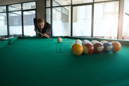 Photo for Concentrated billiard player in fancy clothes preparing to shot billiard ball with cue indoors - Royalty Free Image