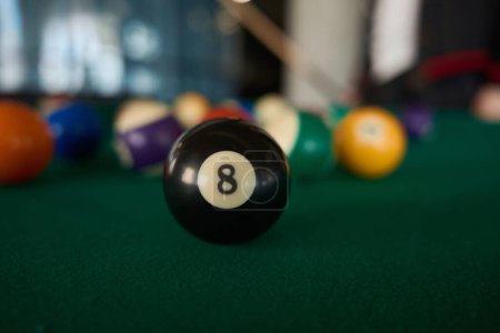 Téléchargez les photos : Vue rapprochée sur boule de billard noire avec numéro 8 sur table de billard sur fond flou de boules de jeux - en image libre de droit