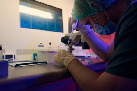 Foto de Trabajador de laboratorio genético agregando células femeninas a la placa de cultivo celular, llevando a cabo investigaciones y observando el desarrollo de células, el crecimiento de embriones - Imagen libre de derechos