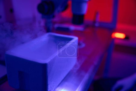 Foto de Vista a la cubeta con nitrógeno líquido para vitrificación de embriones, laboratorio reproductivo en luz ultravioleta - Imagen libre de derechos