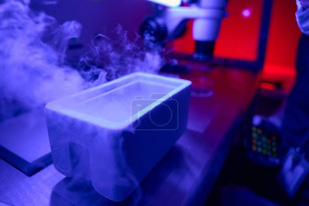 Photo for Cold smoke from liquid nitrogen rising above cuvette for rapid eggs vitrification, fertility and reproduction laboratory - Royalty Free Image